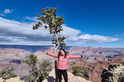 Hier sieht man die Studentin, wie sie mit ausgestreckten Armen auf dem Grand Canyon steht. 
